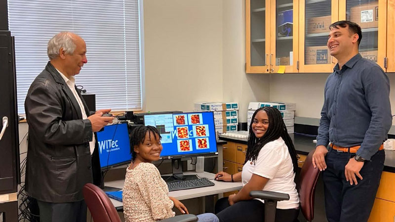 Dr. Karoui and Dr. Akram discussing with Physics graduate student, Ruth, and Chemistry student, Kristen, about fabricated piezoelectric being characterized with Raman Confocal spectroscopy.