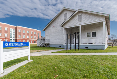 A white house with a sign in front of itDescription automatically generated with low confidence