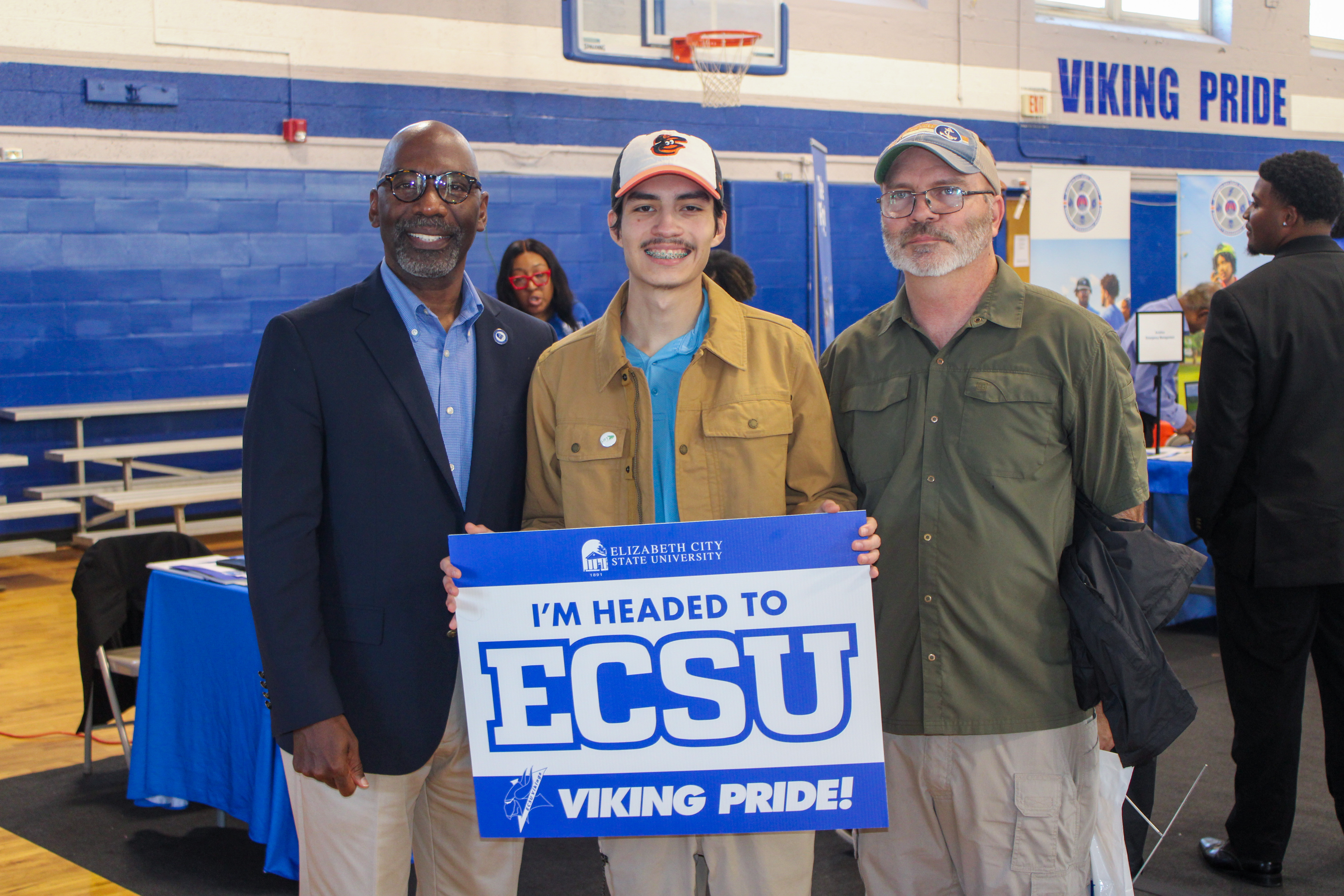 Prospective student poses with the chancellor while holding an “I’m headed to ECSU” sign at an open house.