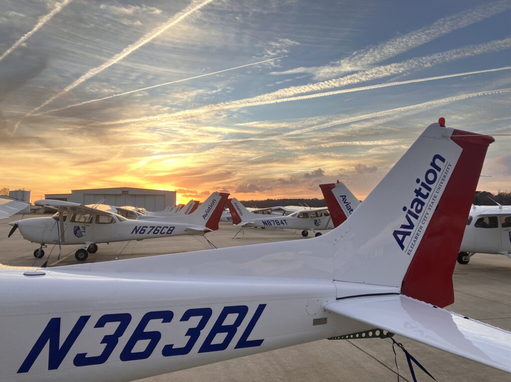 Close up of the tail of an ECSU airplane at the airport with other ECSU planes behind it.