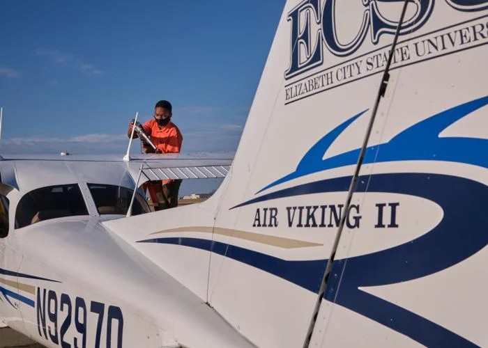 Person checking over an ECSU plane at the airport