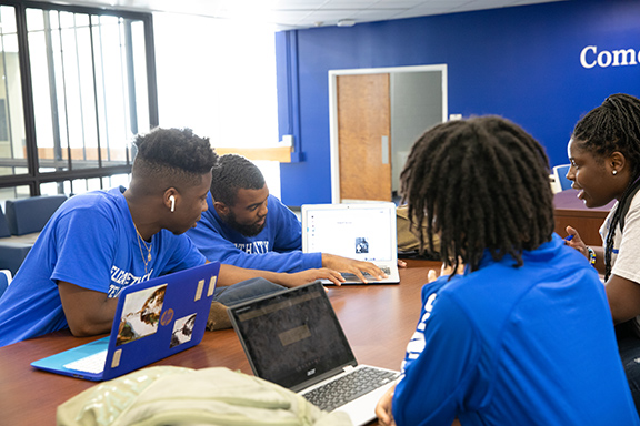 ECSU students sitting at a table together. All on computers, pointing at a screen.