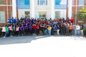 Group photo of Greek members from all fraternities and sororities. They are standing on outdoor stairs of a building.