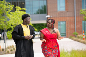 Two Student Government Association representatives, one male, one female, walking together outside on campus.